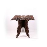 An Indian carved occasional table, with rich vinous carving, on a folding stretcher base, possibly