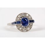 An Art Deco, natural sapphire and diamond ring, the central oval cut stone framed by a halo of old