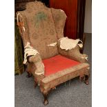 A George II style wing armchair, distressed.