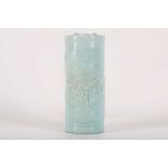 A Chinese cylindrical blue glazed flower holder with landscape decoration in relief, 11cm high