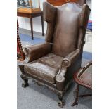 A large George II style stained beechwood and leather covered wing back armchair. Covered in studded