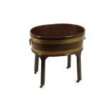 A GEORGE III MAHOGANY AND BRASS BOUND WINE COOLER ON STAND  the oval mahogany cooler or jardiniere
