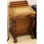 A Victorian walnut Davenport, with carved scrolling front supports, the body with four short drawers