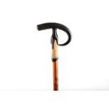 AN UNUSUAL WALKING CANE, the ebonised grip carved with a hand on a fur shaft with pointed ferrule