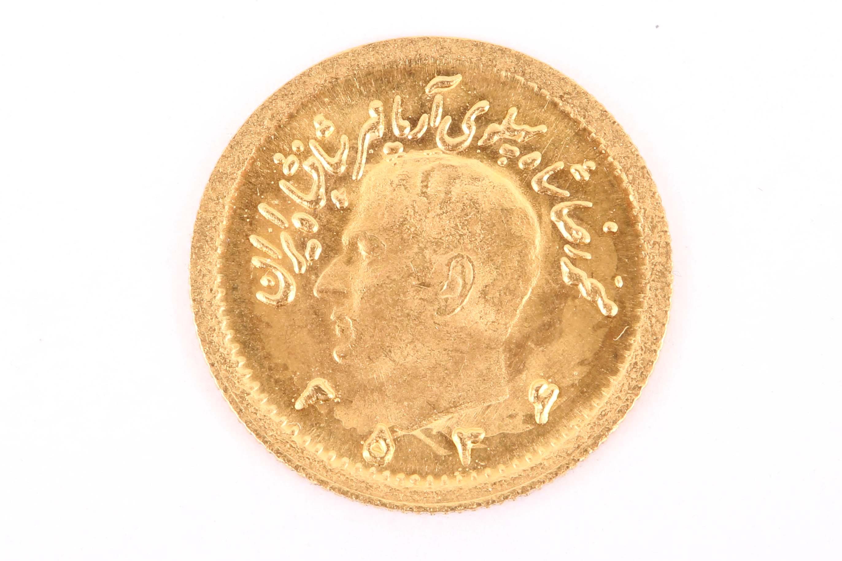A 1970's Iranian high carat gold quarter sovereign shaped commemorative coin, depicting profile of
