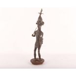 A large African bronze standing figure of a warrior wearing a mask decoration, supplied on drum