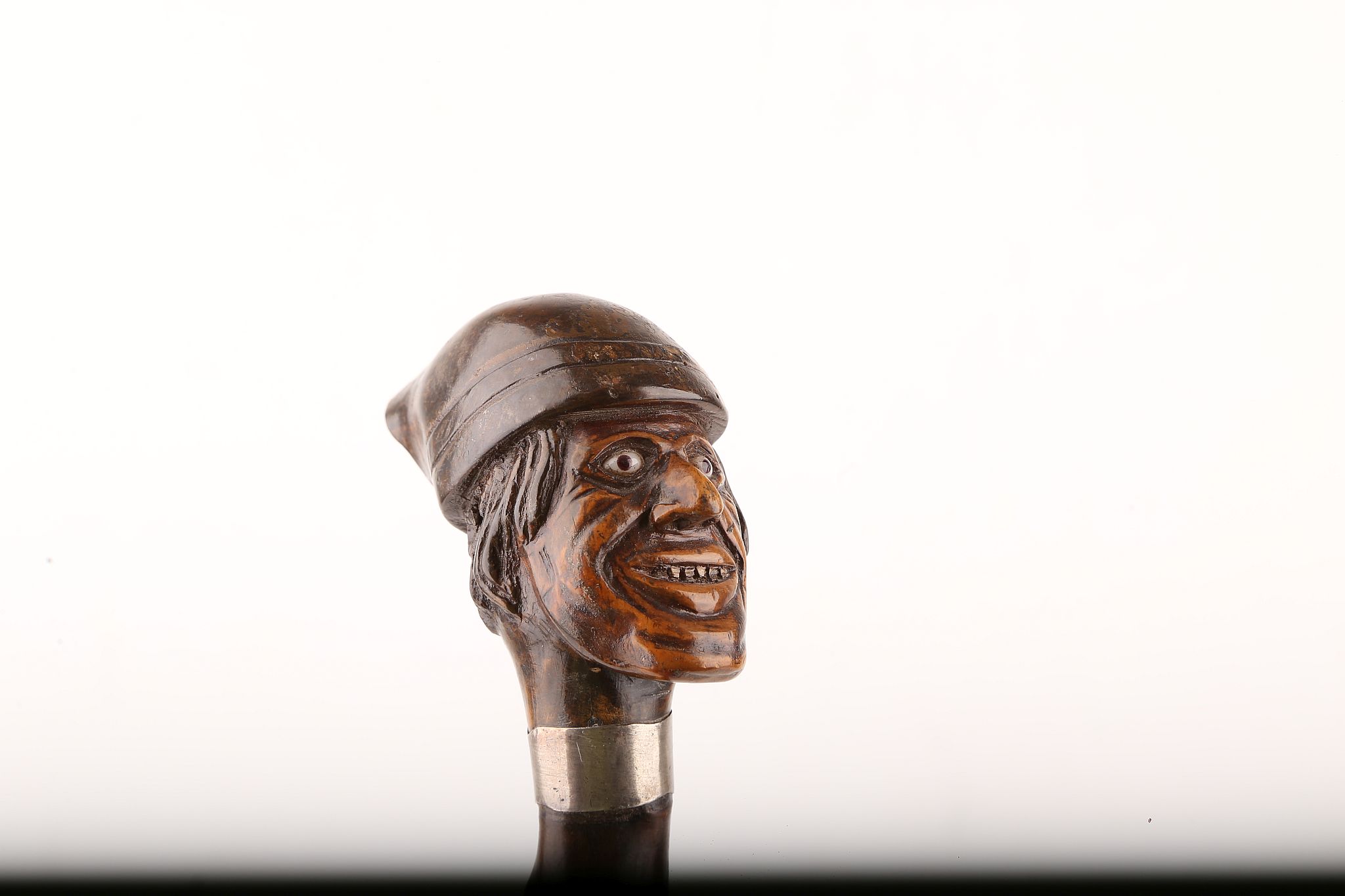 AN INTERESTING FOLK ART WOOD CANE, modelled as a man's head wearing a working hat, early glass eyes,