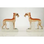 A PAIR OF STAFFORDSHIRE FIGURES OF GREYHOUNDS, mid 19th century, both modelled standing with a