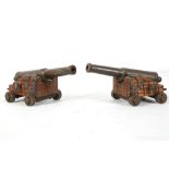 A PAIR OF MINIATURE BRONZE CANNONS, stepped trunnions, bronze wheels, barrel 6" long.