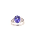 A tanzanite and diamond ring The oval-cut tanzanite, in a four-claw setting, between triangular