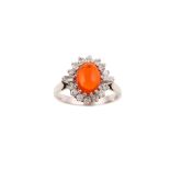 A fire opal and diamond cluster ring The oval cabochon fire opal, within a surround of brilliant-cut