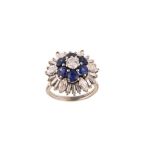 A sapphire and diamond cluster ring, circa 1965 Of tiered form, centrally set with a brilliant-cut