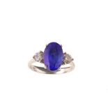 A tanzanite and diamond ring The oval-cut tanzanite, in a four-claw setting, between brilliant-cut