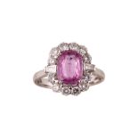 A pink sapphire and diamond cluster ring The cushion-shaped pink sapphire, within a surround of