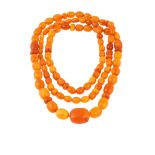 A long amber bead necklace The single-strand of oval and roundel amber beads, ranging in size from