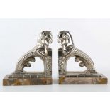 A pair of Art Deco chromed bookends in the form of griffons, mounted on variegated marble bases (