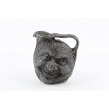 ATTRIBUTED TO MARTIN BROTHERS, a lead double sided face jug, (16 cm high)