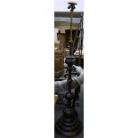 A Chinese bronze floor standing lamp, having repousse details and supported on a 3 tier wooden base,