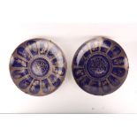 A pair of Oriental porcelain export wall chargers, painted on blue lustre ground with panels of