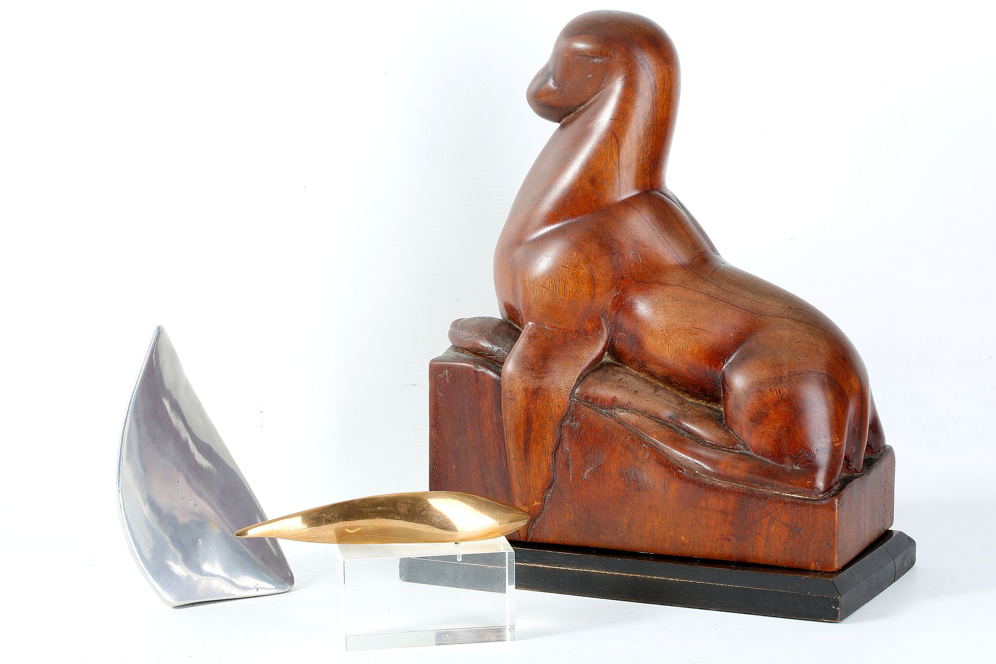 A carved hardwood 20th Century sculpture of a seal resting with a salmon, signed to base 'E Mehmet