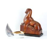 A carved hardwood 20th Century sculpture of a seal resting with a salmon, signed to base 'E Mehmet