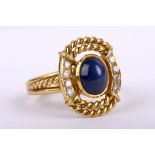 A sapphire and diamond dress ring, circa 1985 Centrally collet-set with an oval cabochon sapphire,