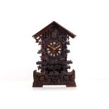 A 19TH CENTURY BLACK FOREST CARVED WOOD CUCKOO CLOCK of typical form with pitched roof over the