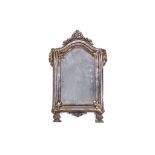 AN 18TH CENTURY ITALIAN BAROQUE SILVERED METAL MIRROR the moulded and arched frame surmounted by a