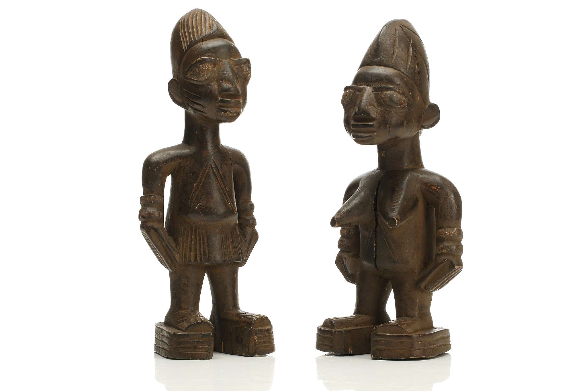 TWO WOODEN IBEJI FIGURES, NIGERIA Each of stylised form, with incised decoration, large eyes and