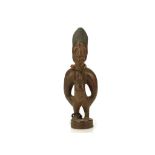 A WOODEN IBEJI FIGURE, NIGERIA With a high coiffure and large eyes and the face with scarifications,
