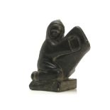 AN INUIT CARVED SOAPSTONE WHALE RIDER The figure depicted wearing a hood and gloves, holding onto