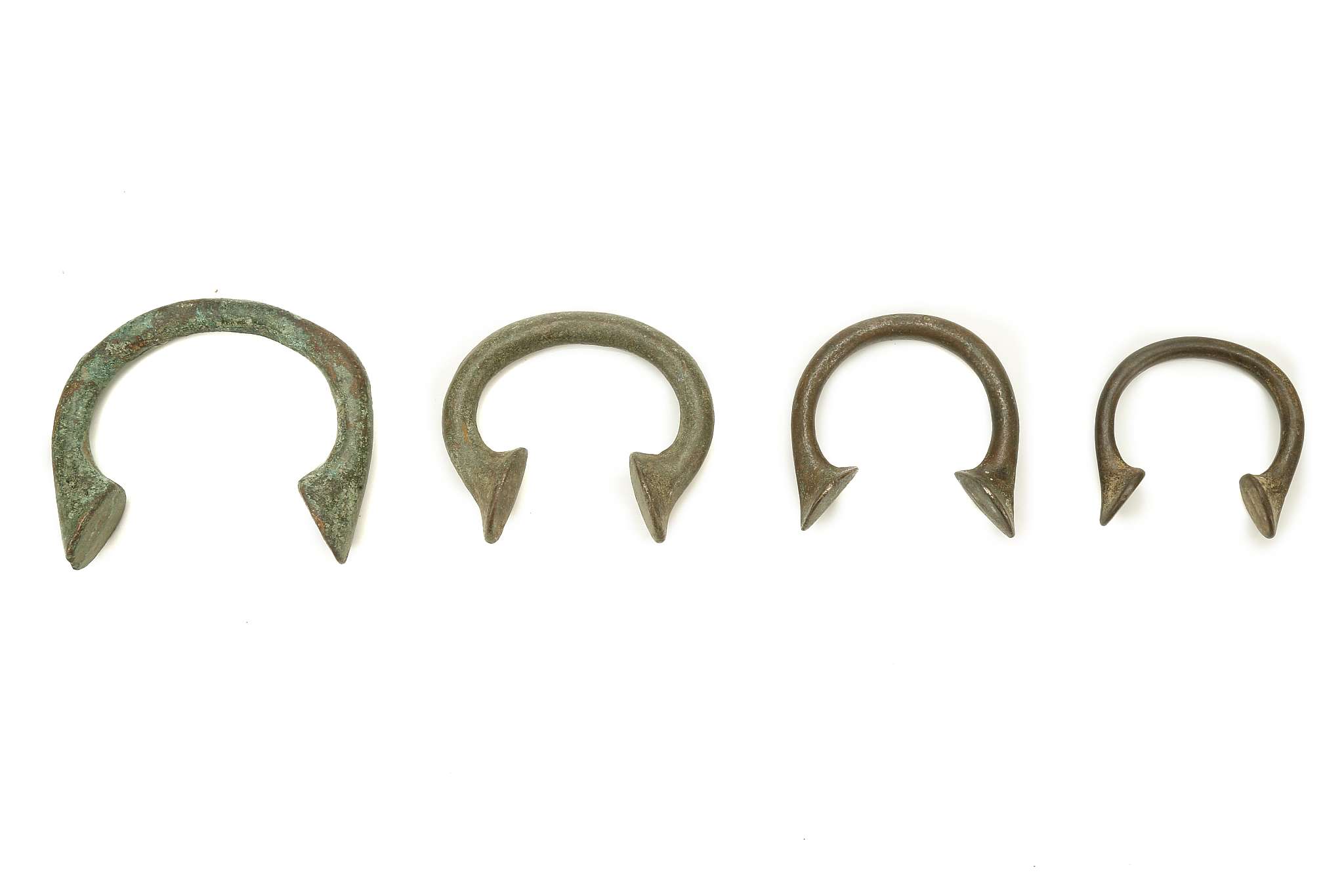 FOUR PIECES OF MANILLA CURRENCY, NIGERIA Each of penannular form, with flattened terminals, 6.2cm-