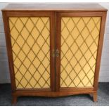 A George III satinwood banded mahogany side cabinet, enclosed by two brass grill doors on splay