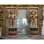 A pair of decorative carved wood putti, with glass eyes on acanthus bases, 87cm.