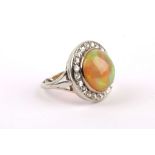 A white gold opal dress ring, the cabouchon stone with diamond border.