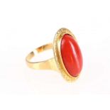 A coral dress ring, The oval coral corallium rubrum, within an engraved surround, stamped 750,