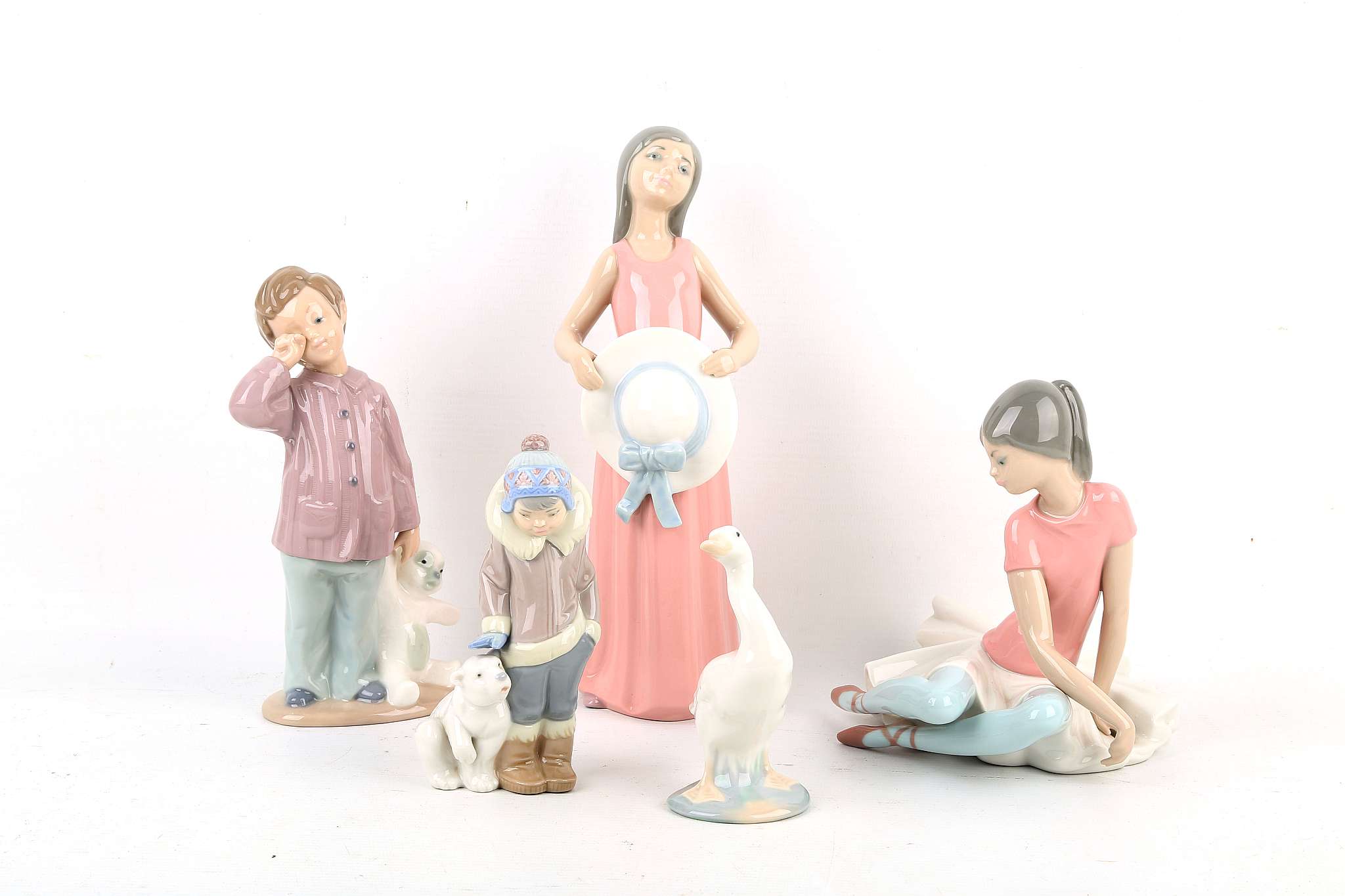 A Lladro porcelain model of a ballerina, a model of a girl holding a hat, a little model of a