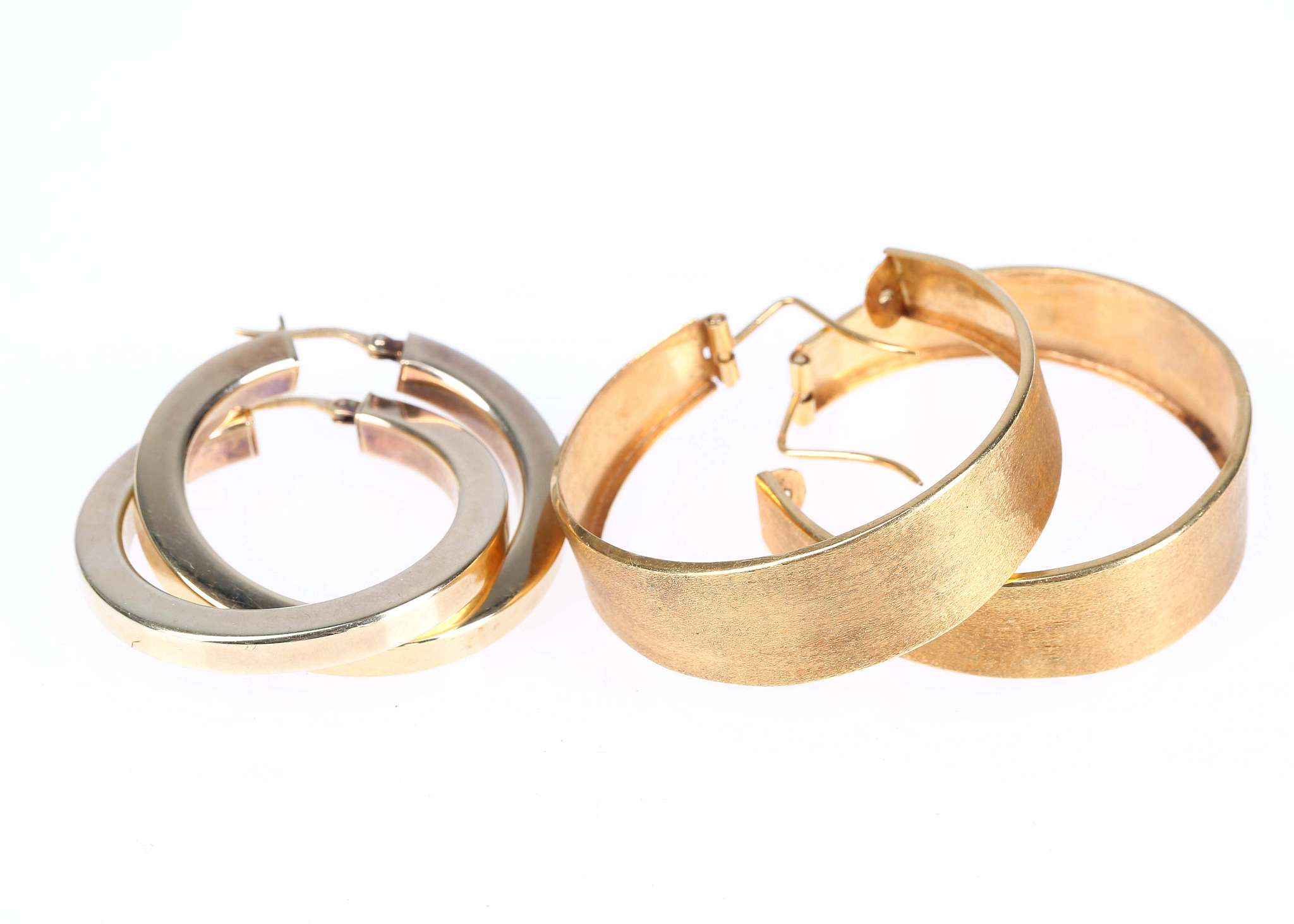 Two pairs of hoop earrings, One of wide brushed design, stamped 18K, the other of silver gilt,