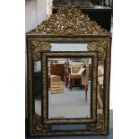 A Dutch ebony and repousse gilt framed cushion mirror, with top pediment in 17th Century manner,