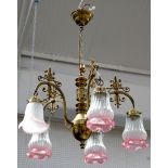 An Edwardian style brass chandelier, with five white and pink glass shades hanging from individual