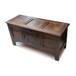 A late 17th / early 18th Century oak coffer, with triple panelled hinged top and geometric front, on