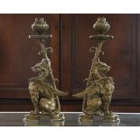 A pair of 19th Century cast bronze models of griffin centrepieces, formed as candlesticks, raised on