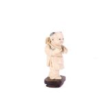 A Chinese carved ivory standing carved boy holding a peach branch, late 19th / early 20th Century,