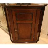 A George III mahogany hanging corner cabinet, enclosed by a twin panelled door, 102cm high.