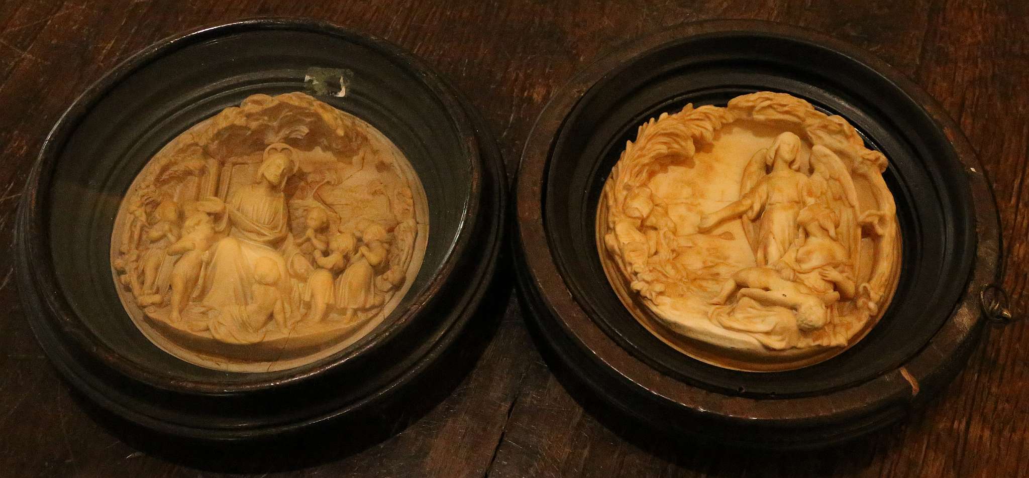 A pair of Victorian circular relief moulded plaster plaques of Christ and an angel, ebonised