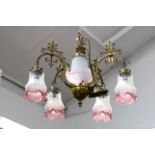 An Edwardian style brass chandelier, with five white and pink glass shades hanging from individual