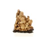 A Chinese soapstone carving of a Buddha seated beside a sack with three boys climbing over his body.