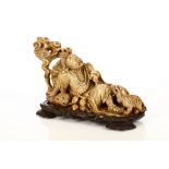 A Chinese soapstone carving of a seated figure holding a bat beside a lion with a double gourd