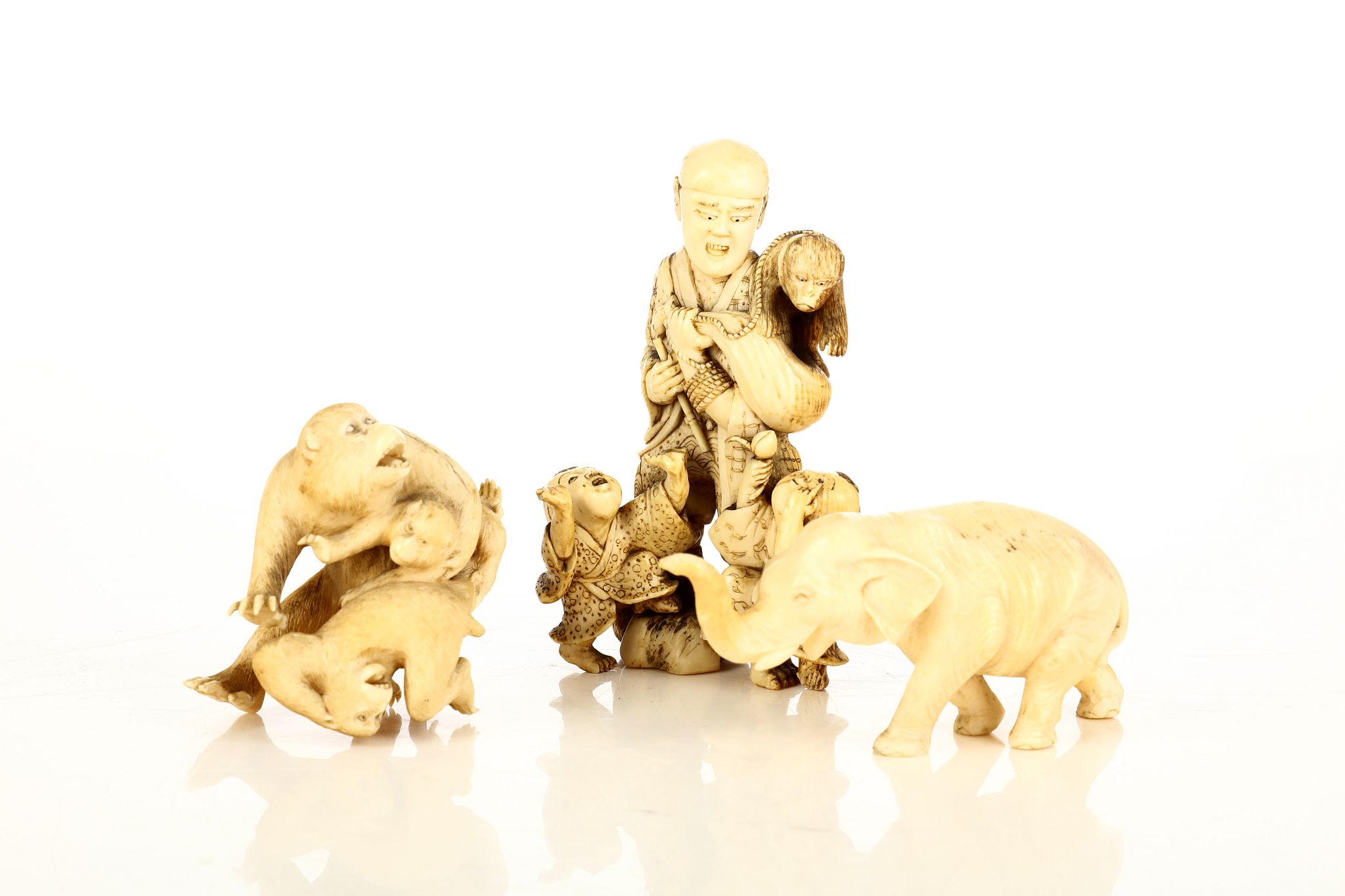 Three Japanese ivory okimono carvings. Meiji period. Depicting monkeys, an elephant and a monkey