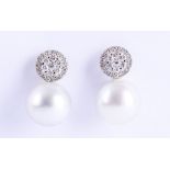 A pair of cultured pearl and diamond earrings, Each 14.3-14.4mm cultured pearl, surmounted by a